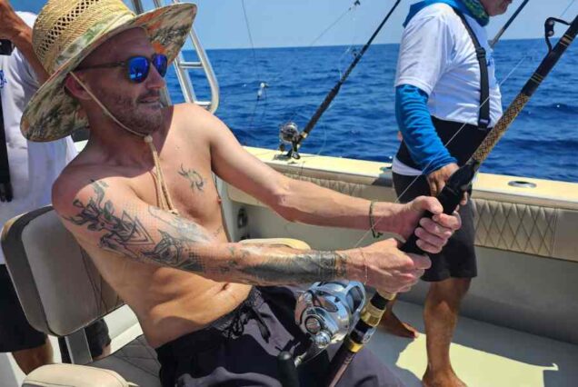 man reeling in fish on 6 hr deep sea fishing charter