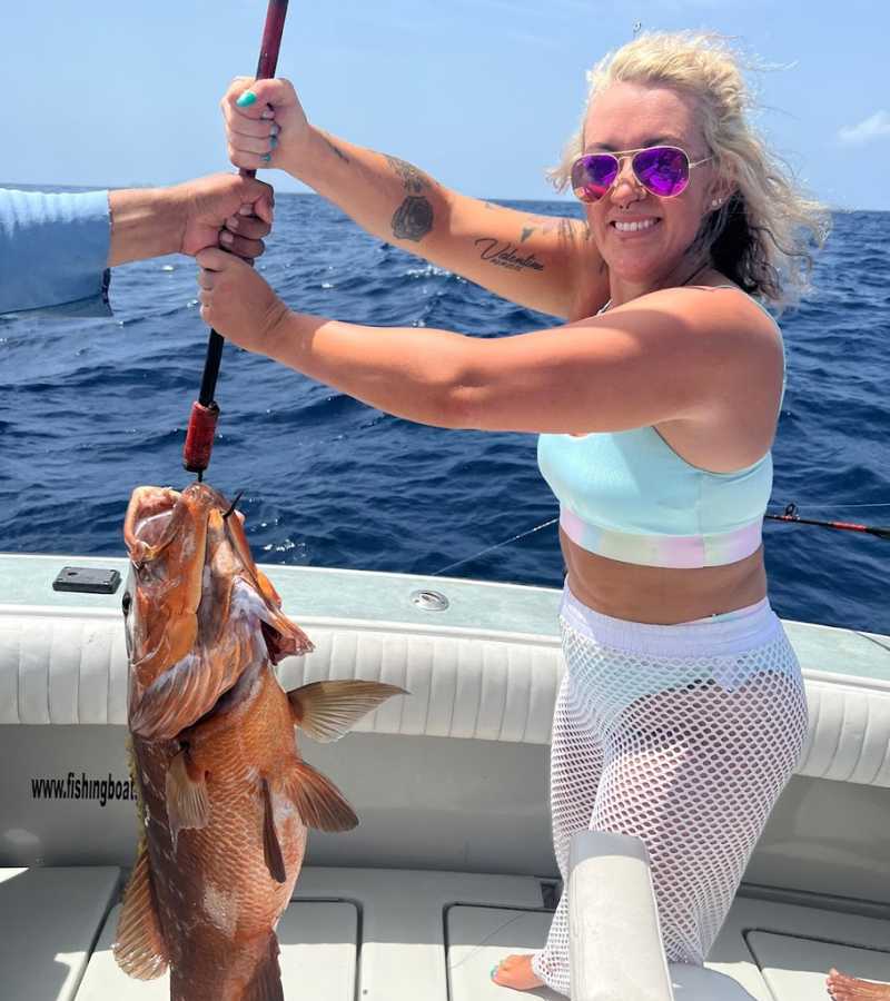 woman holding fish caught while on charter fishing boat in Cancun