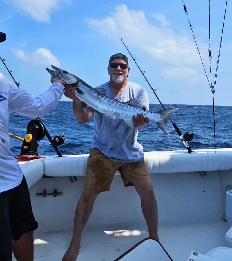 man holding fish caught on cancun charter fishing boat with new fishing gear