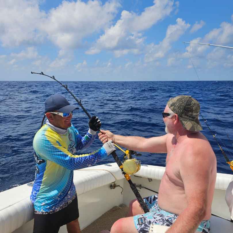 tourist on deep sea fishing boat casting a line into ocean while in Cancun Mexico