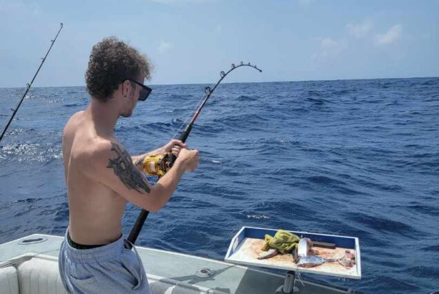 man using live bait to reel in fish while on a private fishing charter and boat tour while vacationing in Cancun, MX
