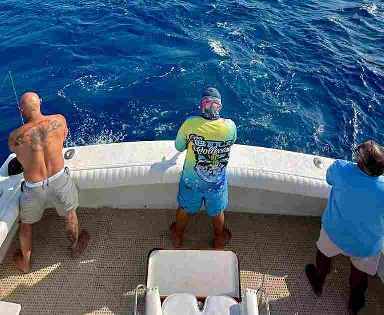 men on back of fishing boat comparing deep sea vs sport fishing in Cancun