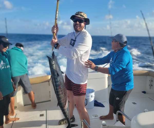 man holding fish and fishing rod while on best fishing charters in quintana roo cancun mexico